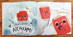 Une page d'un livre illustré avec un personnage rouge aux yeux ronds et des bulles de dialogue, accompagnée de l'expression 'ATCHOUM!' et le texte 'la poussière!'