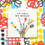Couverture d'un livre intitulé 'La main qui dessine', entourée de motifs colorés en rouge, jaune, noir et bleu.